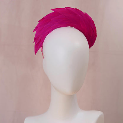 A bright magenta feather headband displayed on a white mannequin head against a soft beige background.