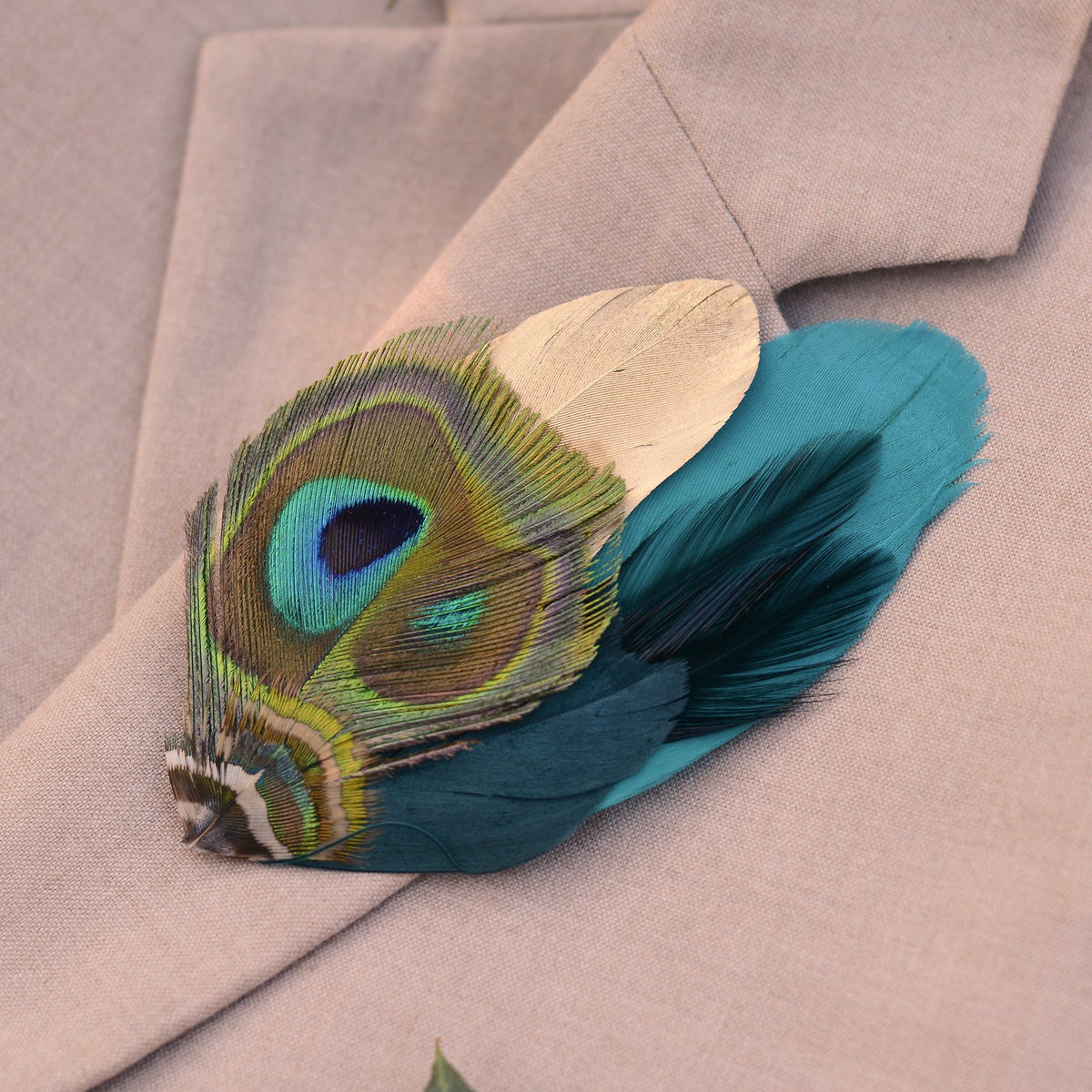 Gold and Teal Peacock feather brooch on a beige blazer