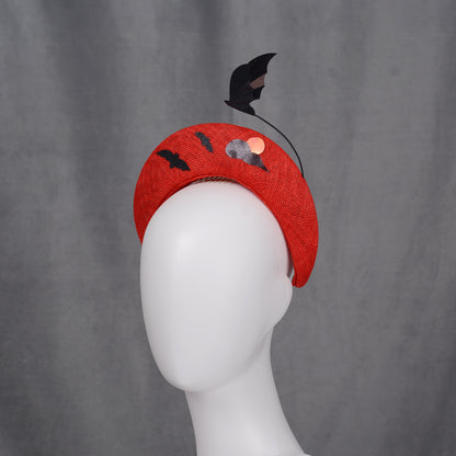 A red halo headband decorated with bat and cloud motifs. The headband has a curved form and is embellished with black bat silhouettes on the back and a bat-shaped decoration rises from the headband.