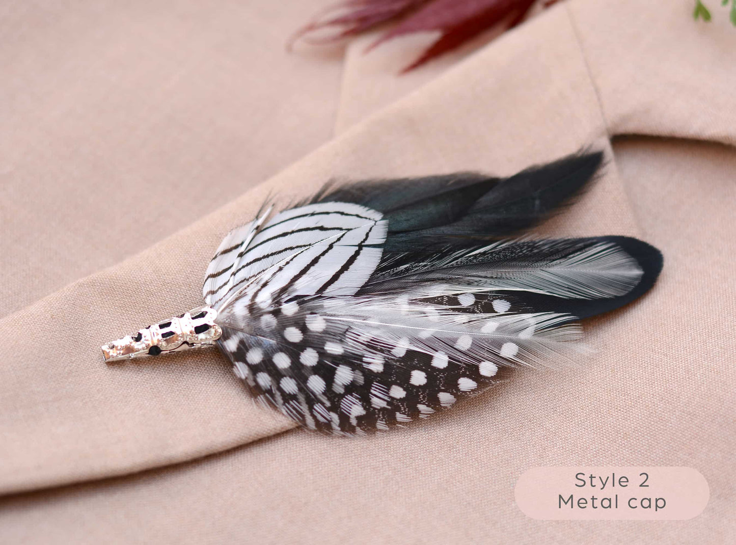 close-up of black and white feather lapel pin  accessory with metal cap on beige fabric