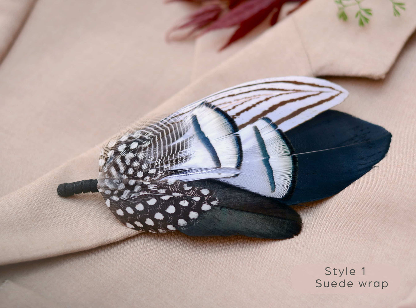Large black and white feathered brooch on a beige fabric background