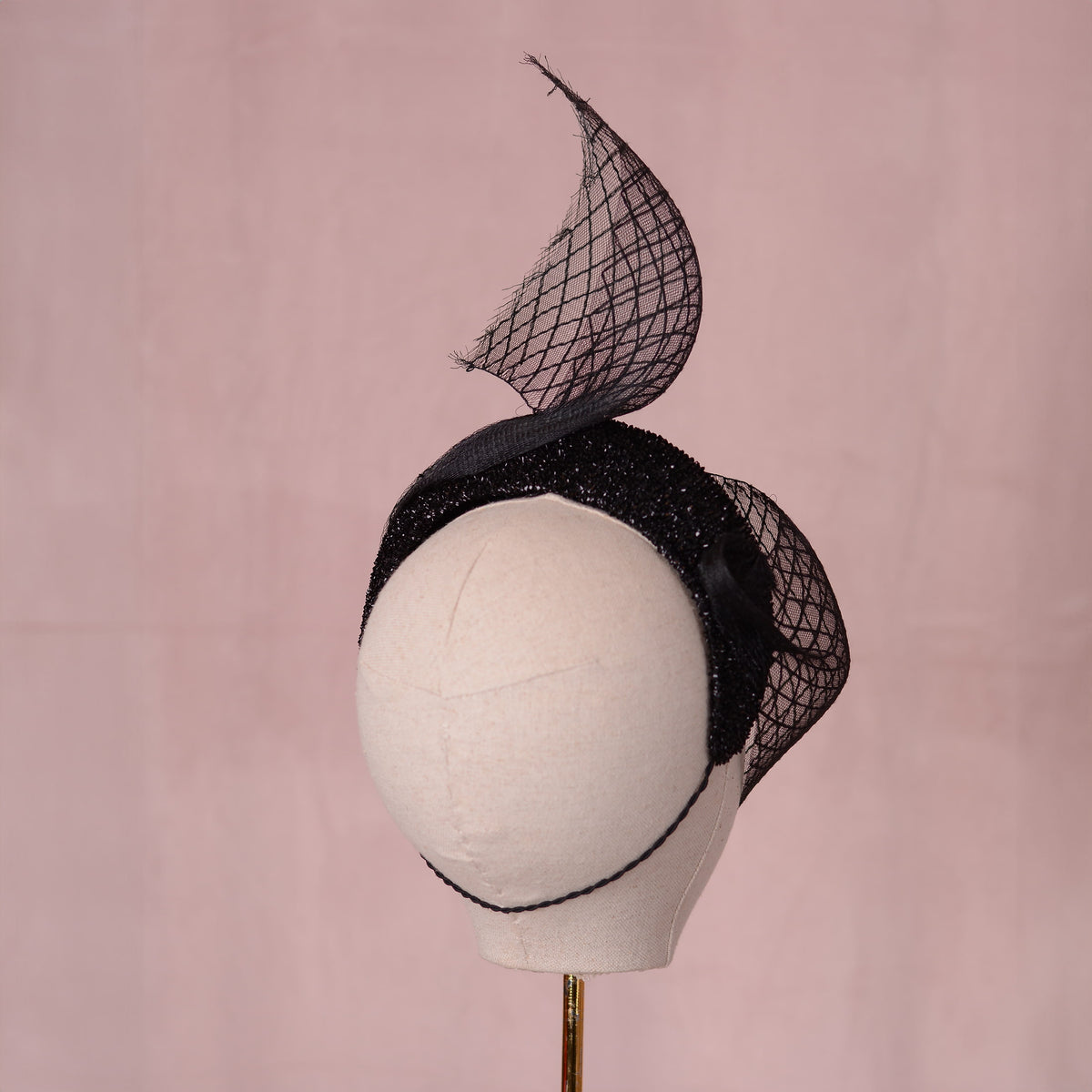 Back veiw of a headband fascinator with sweeping diamond net veil. The hat is secured with a hat elastic.