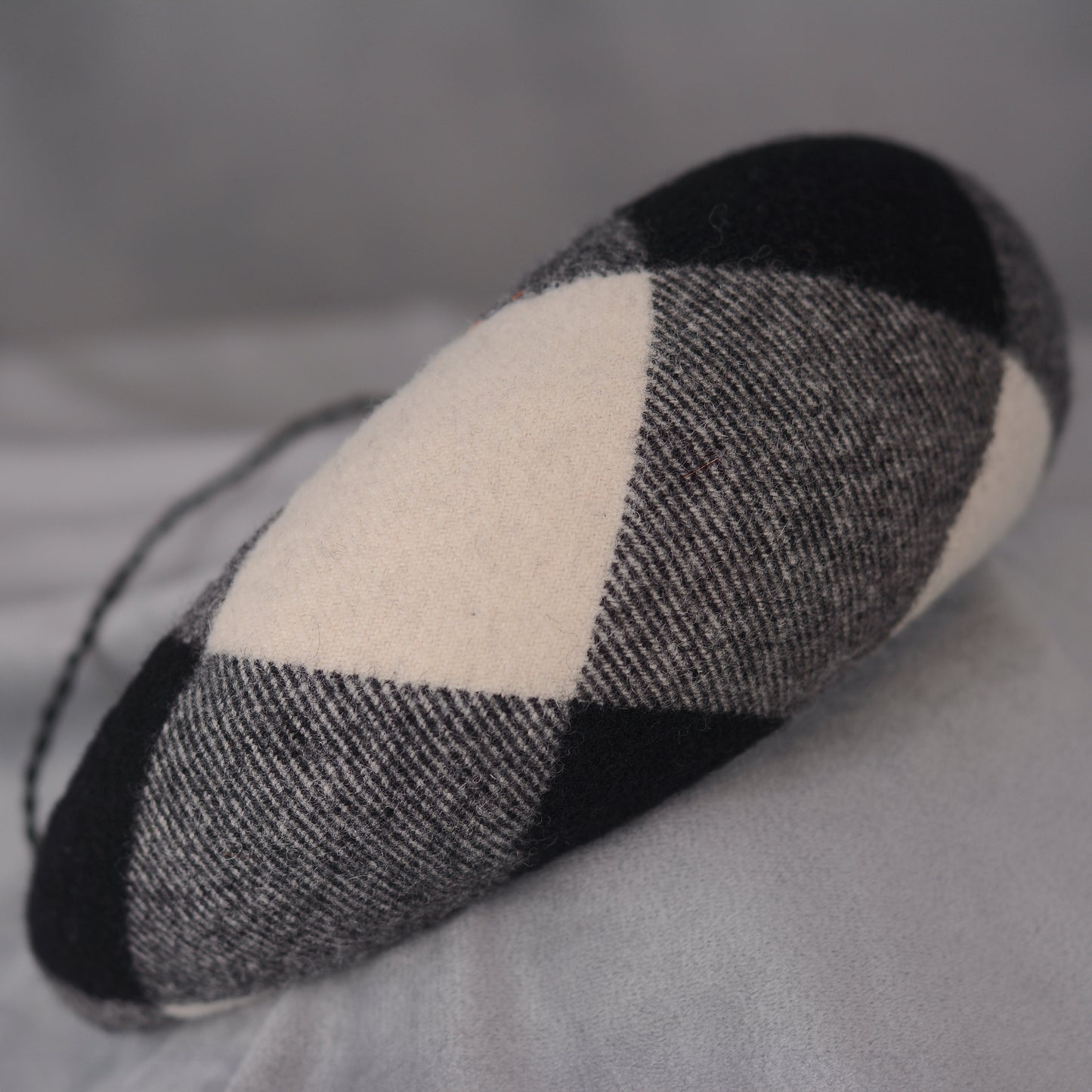 A black, white, and grey checked wool headband fascinator. The hat is displayed on a white mannequin head. The checked pattern is made up of large squares.