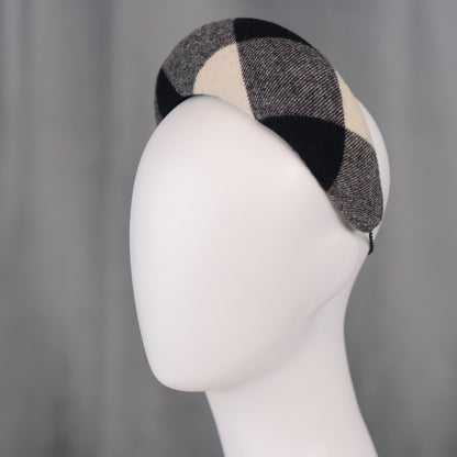 A black, white, and grey checked wool headband fascinator. The hat is displayed on a white mannequin head. The checked pattern is made up of large squares.