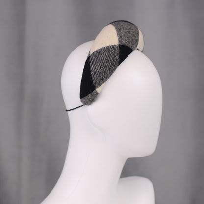 A black, white, and grey checked wool headband fascinator. The hat is displayed on a white mannequin head. The checked pattern is made up of large squares.