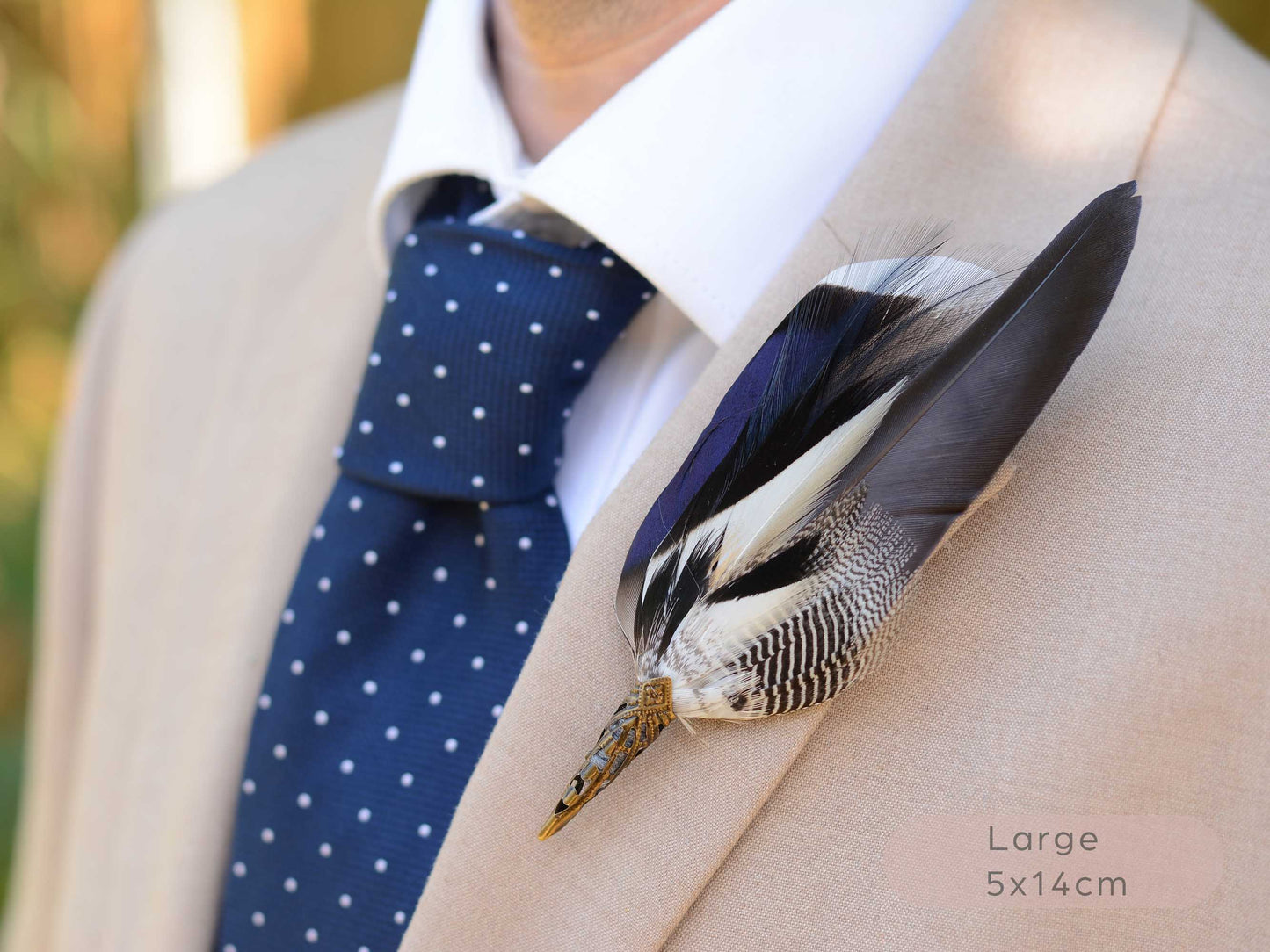 A close-up of a beige suit jacket with a white dress shirt and a navy blue polka-dot tie, featuring a large decorative feather boutonniere pinned to the lapel. The text 'Large 5x14cm' is visible in the bottom right corner.