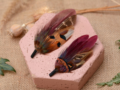 Pink hexagonal stone with burgundy and pheasant feather buttonholes  on a textured beige background