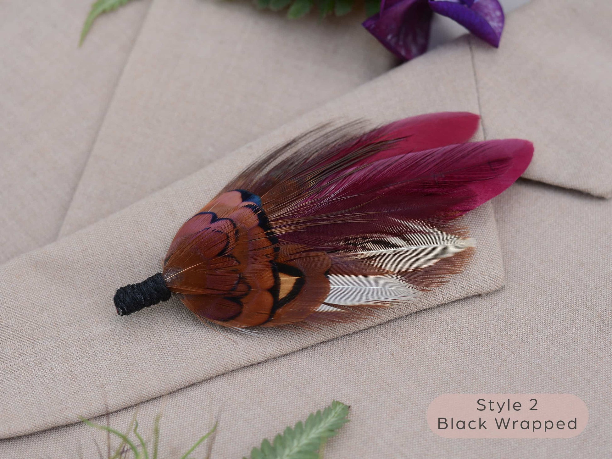 Pheasant feather brooch pin with black wrapping on a textured surface