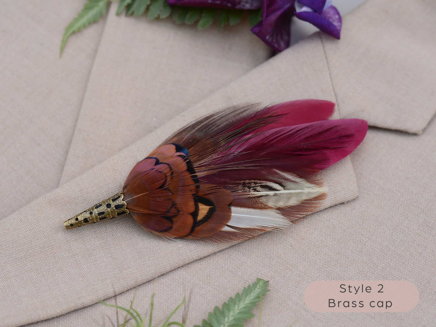 Feathered boutonniere with brass cap on a beige fabric background