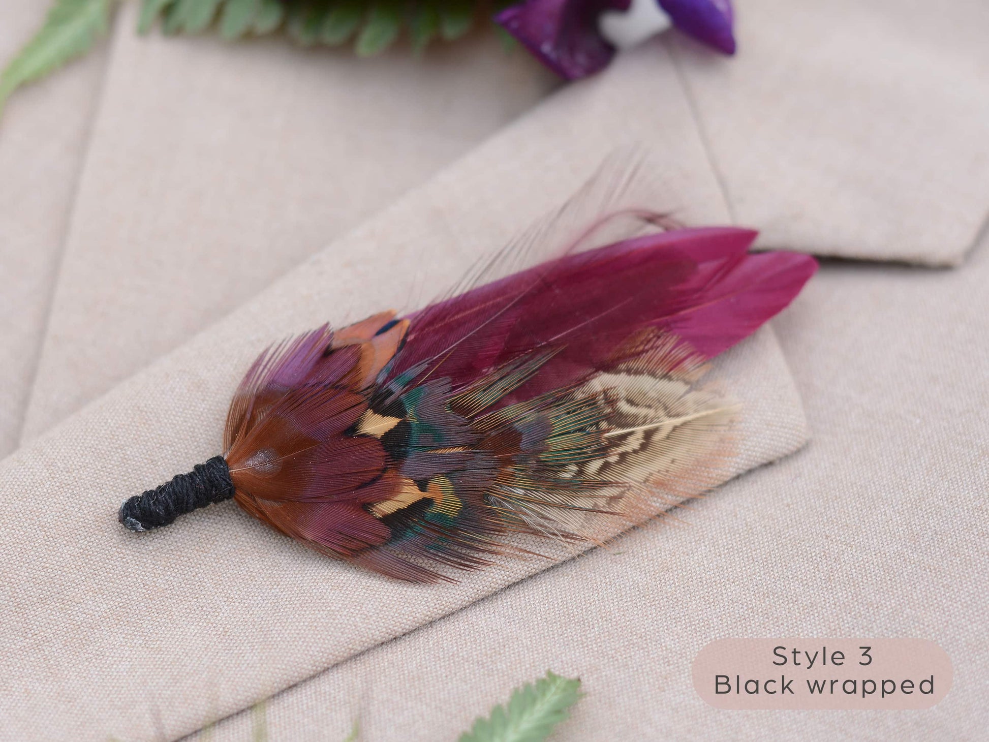 Feathered boutonniere on a beige fabric background with black string wrapped stem