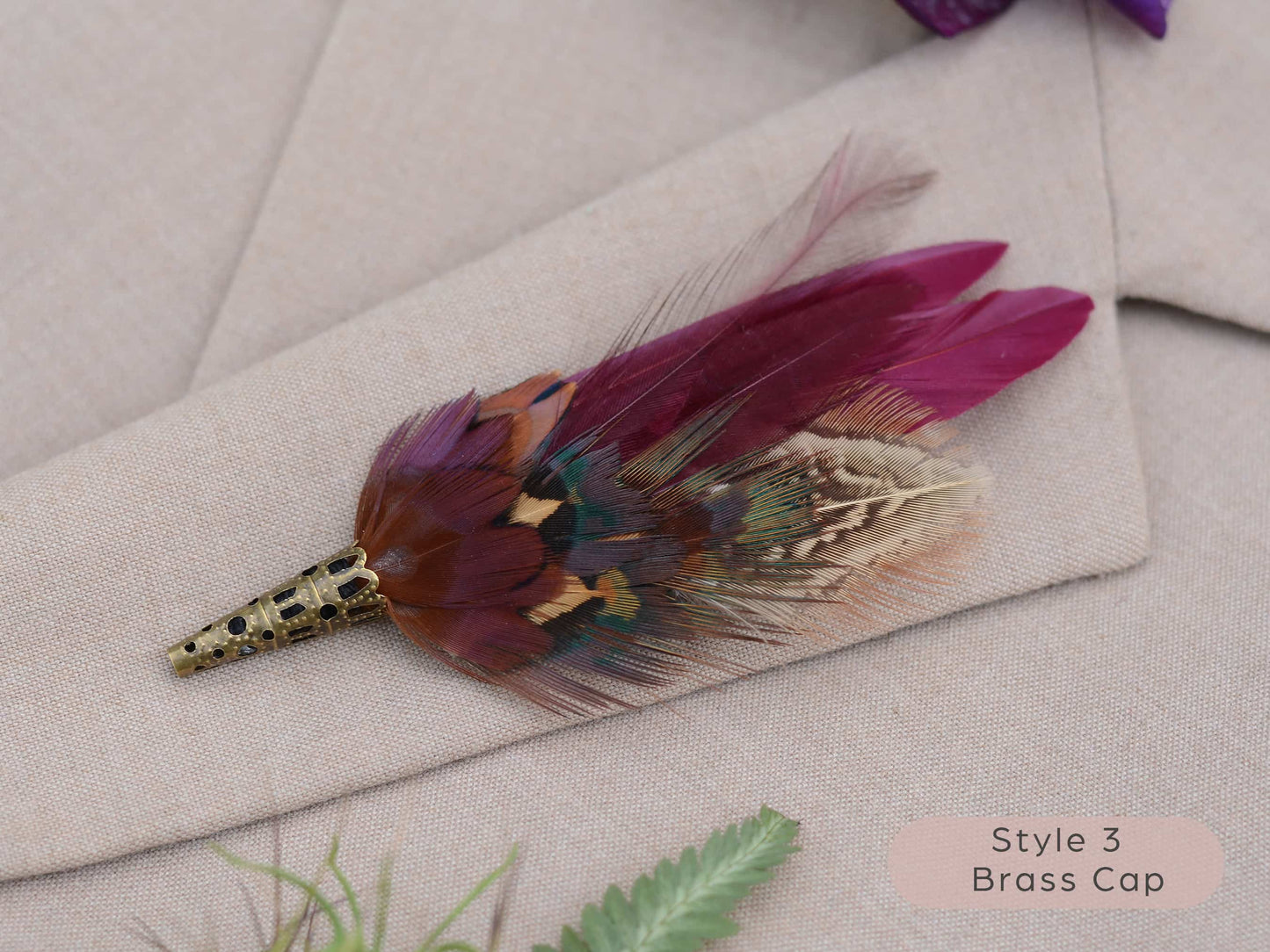 Feathered brooch with brass cap on a light fabric background