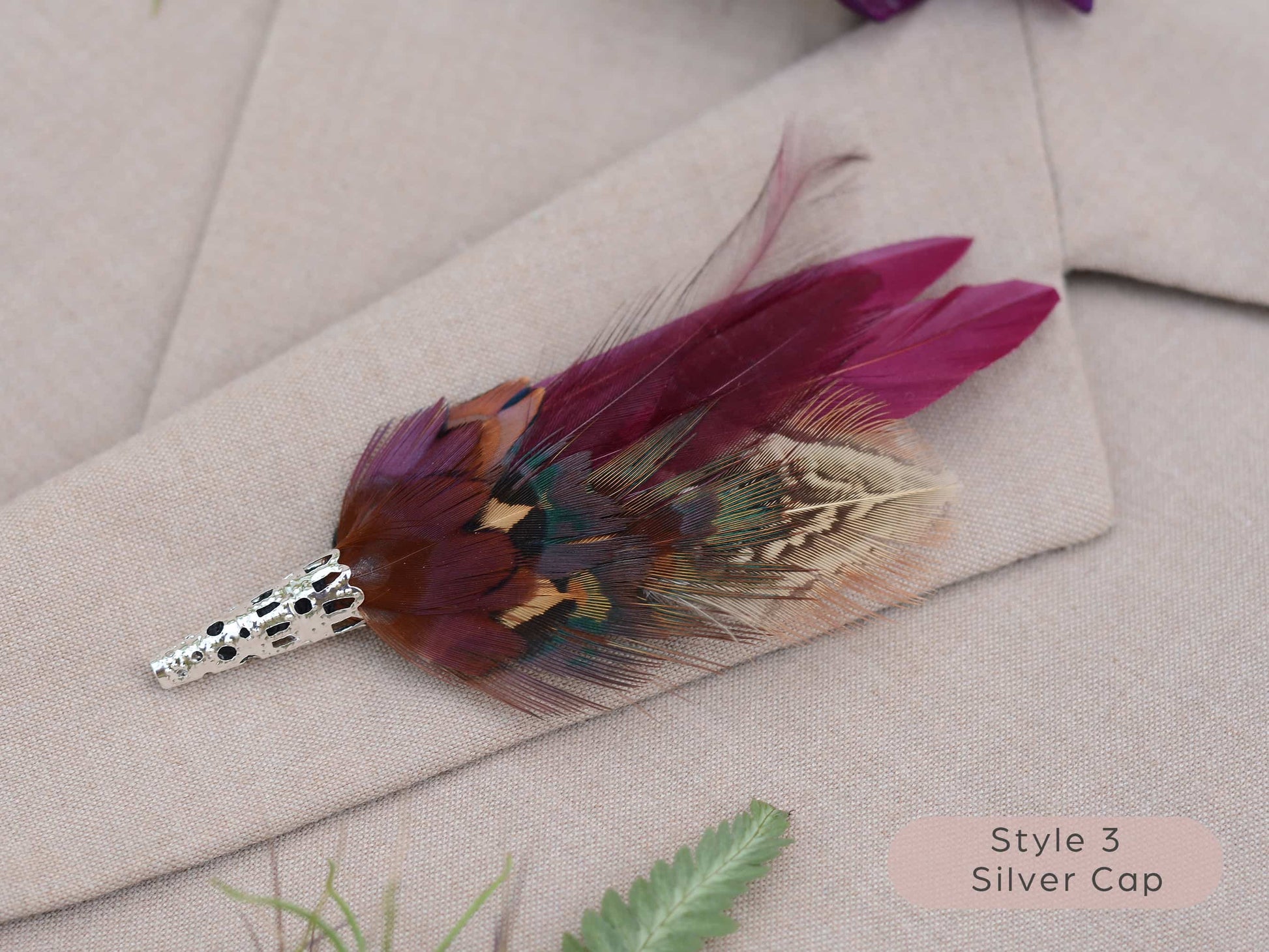 Feathered brooch with silver cap on a light fabric background