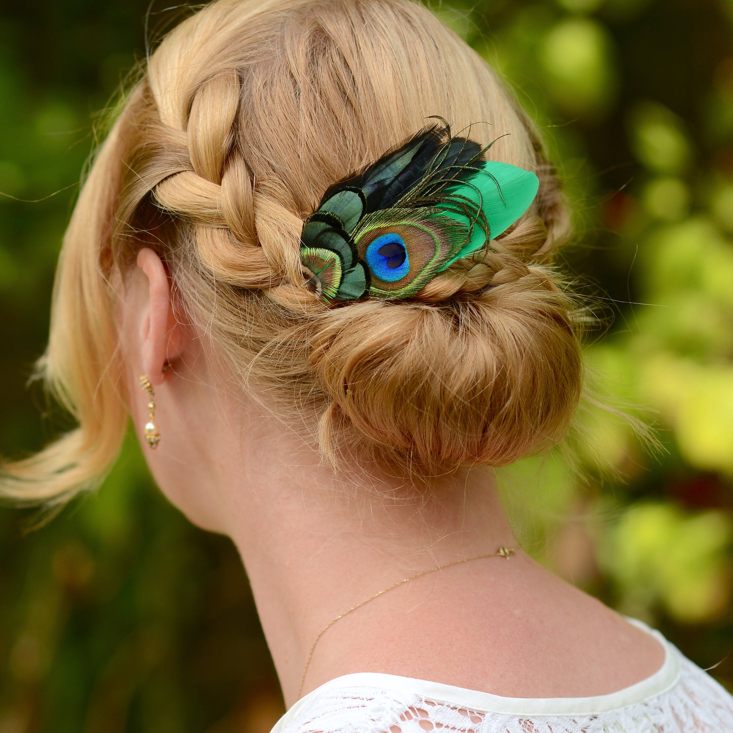 blonde braided wedding hair with feather hair clip with peacock eye in emerald green gold and blue 