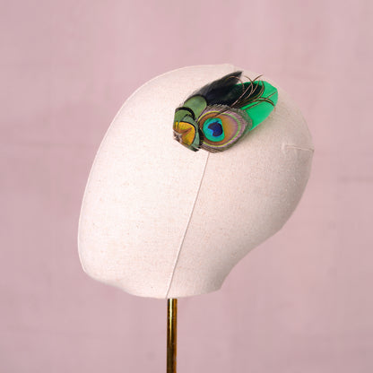 feather fascinator  with peacock eye in emerald green gold and blue  on a canvas mannequin head