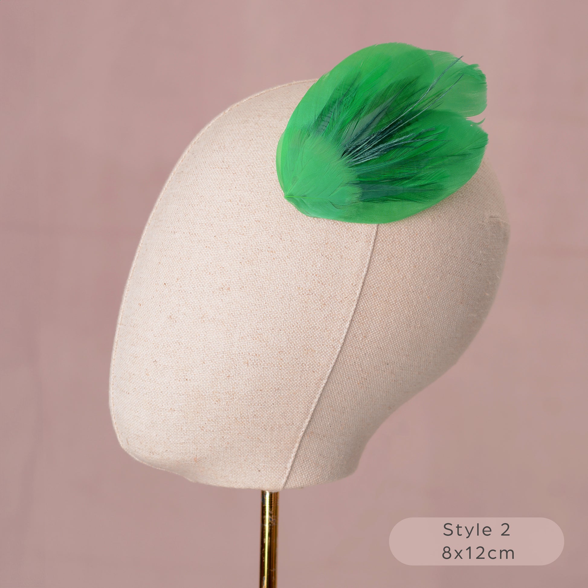 Green feathered hair accessory on a mannequin head against a pink background