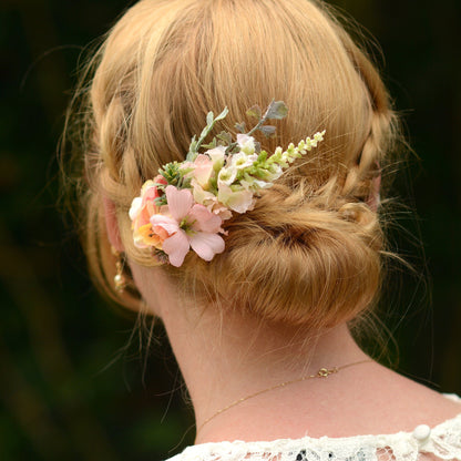Woman with a floral hairpiece in her blonde hair, wearing a white lace top.