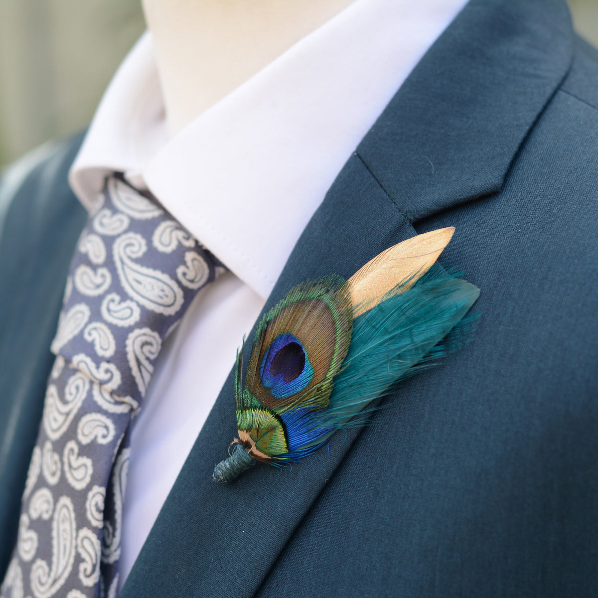 Gold and teal peacock feather groom's wedding boutonniere pinned to a teal suit jacket.