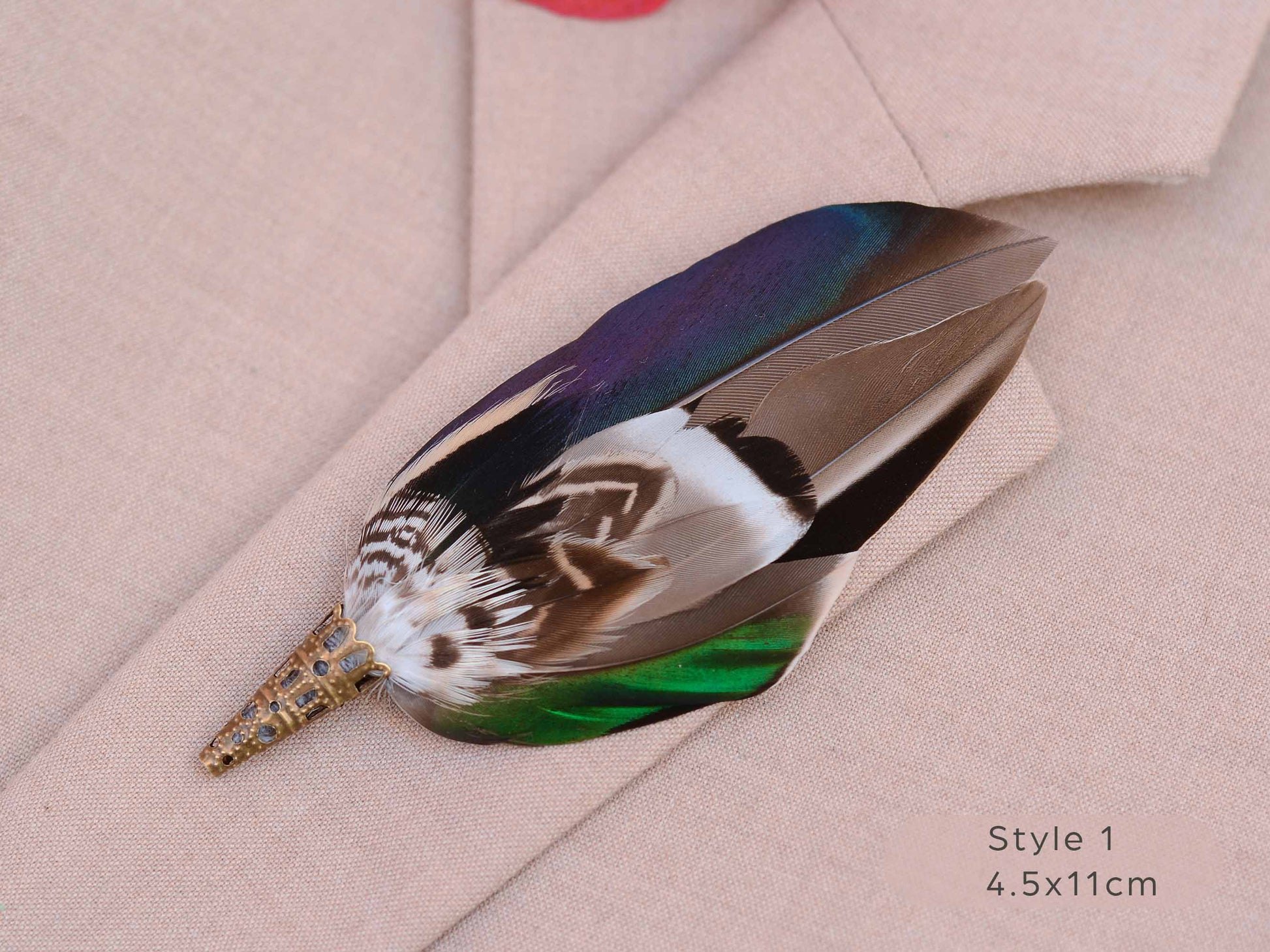 Close up of duck feather brooch pin with iridescent blue and green feathers on a beige jacket.