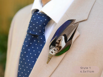 Close up of duck feather brooch pin with iridescent blue and green feathers on a beige jacket paired with a blue polka dot tie.