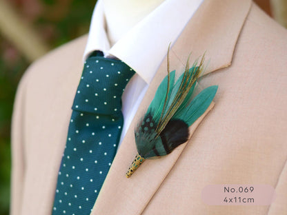 Man wearing a beige suit with a green polka dot tie and a green feather boutonniere.