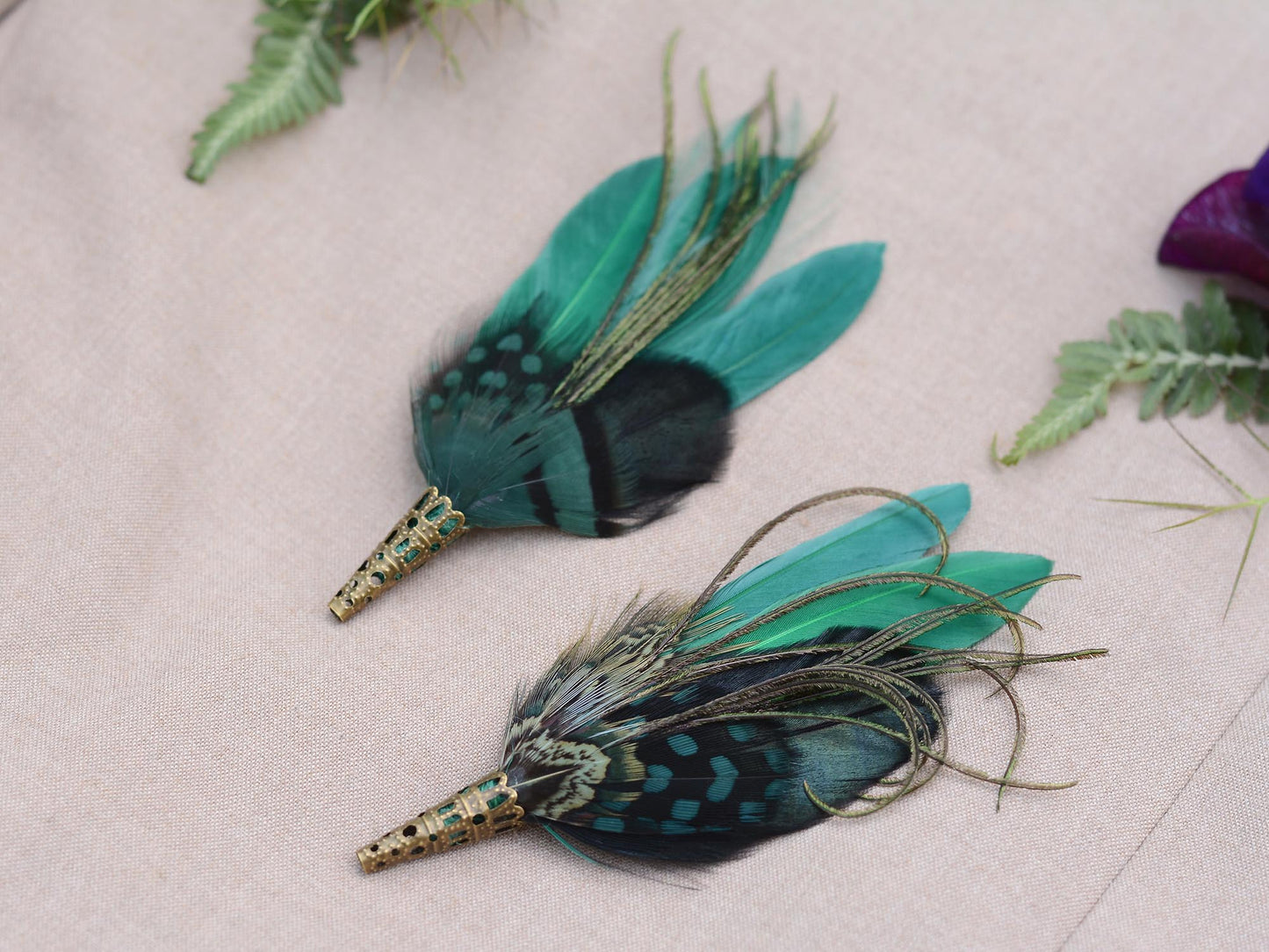 Two green feathered boutonnieres on a light background