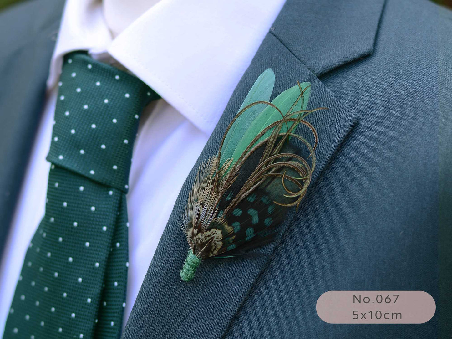 Green feathered boutonniere on a suit lapel with a green tie and white shirt.