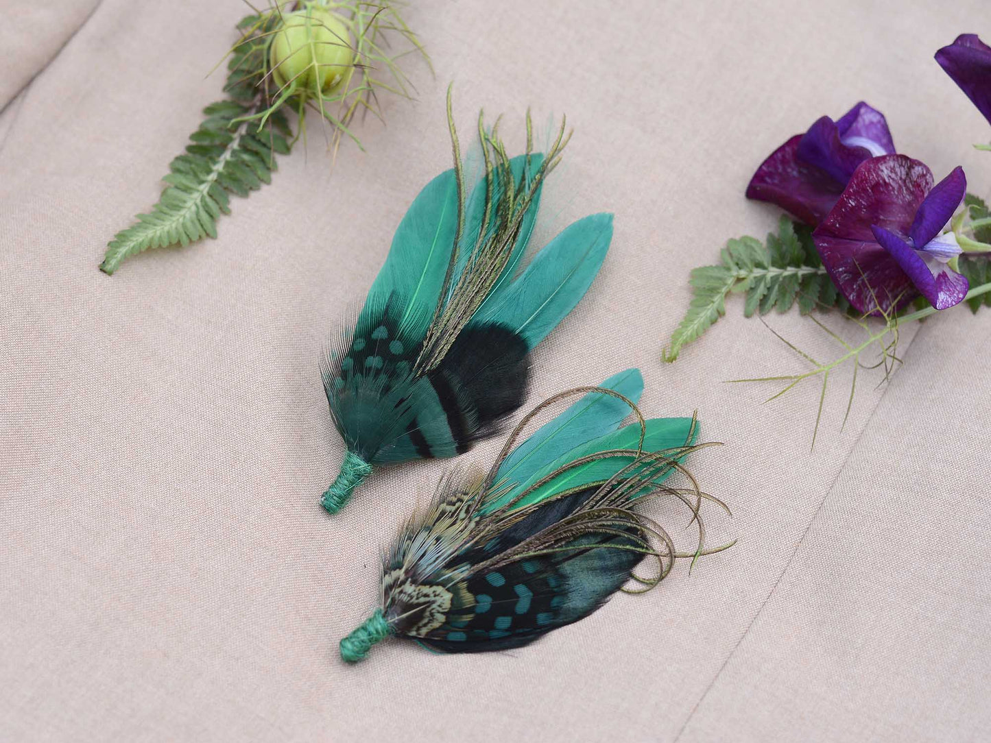 Two green feathered boutonnieres on a light background
