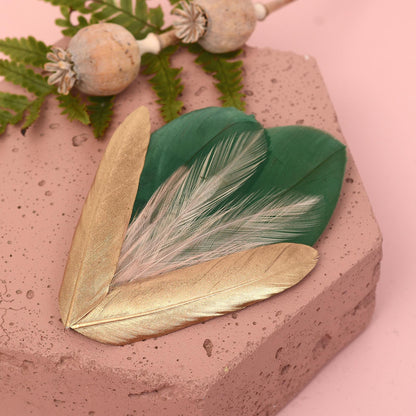 Feather hair clip with layered green, blush pink and gold feathers.