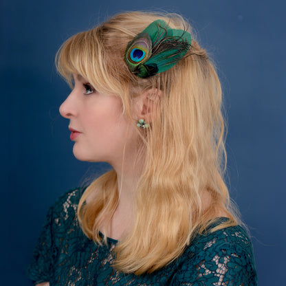 Woman with a green peacock feather fascinator  against a blue background