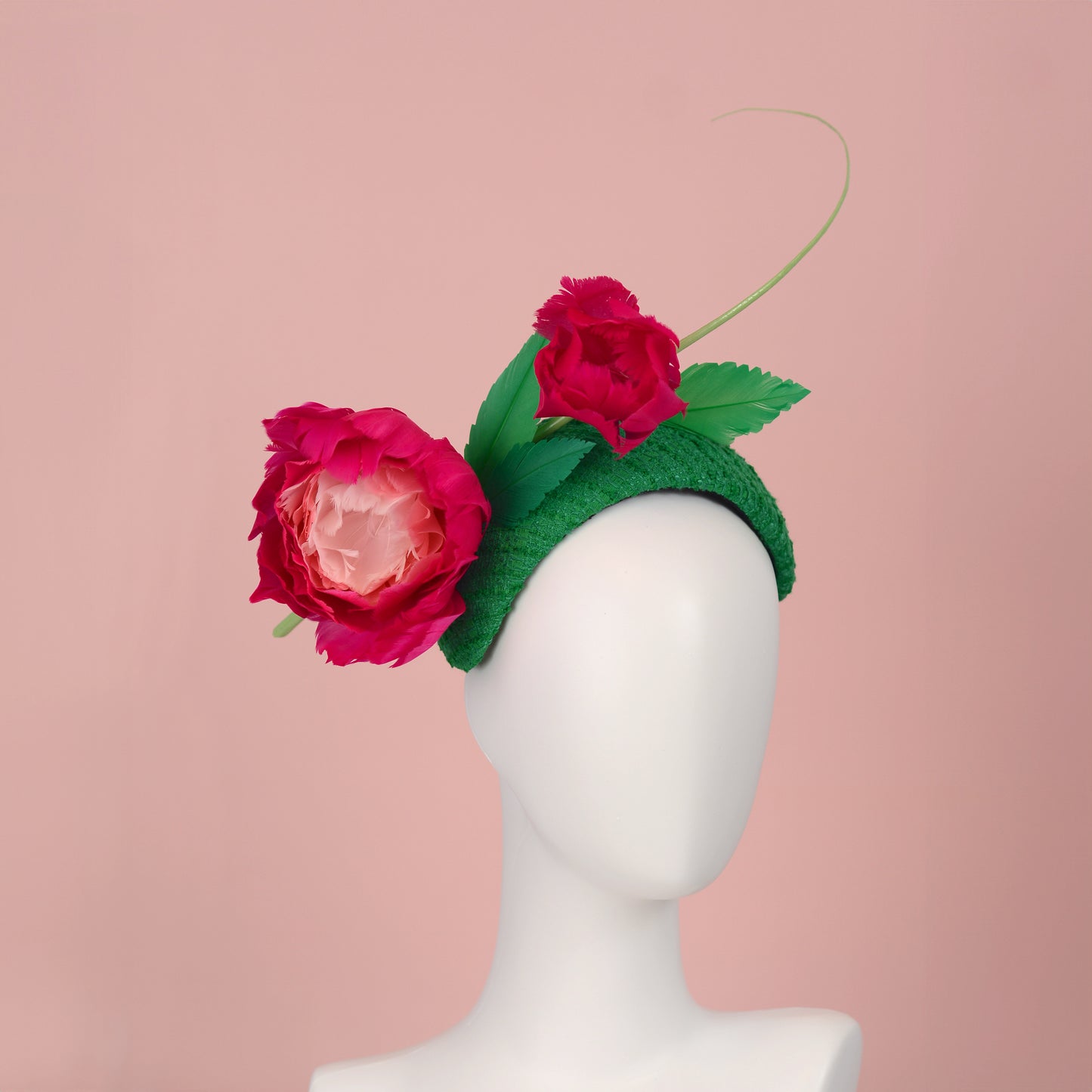 Floral headband with pink flowers and green leaves handmade from goose feathers on a mannequin head against a pink background