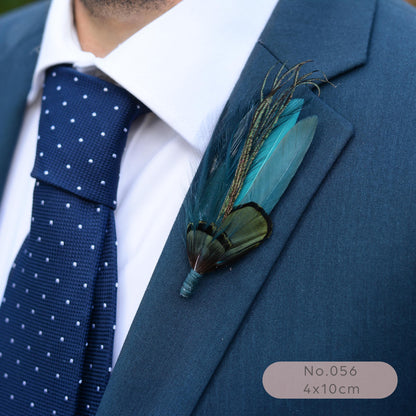 A close-up of a men's formal outfit featuring a blue suit jacket, a navy blue polka dot tie, and a white dress shirt. A decorative feather boutonniere with teal, green.