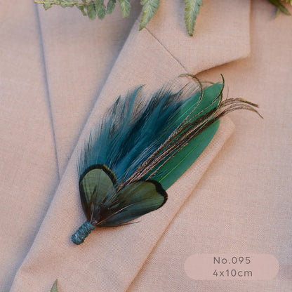 A decorative feather brooch with teal, green, and black feathers, pinned to a beige blazer. 