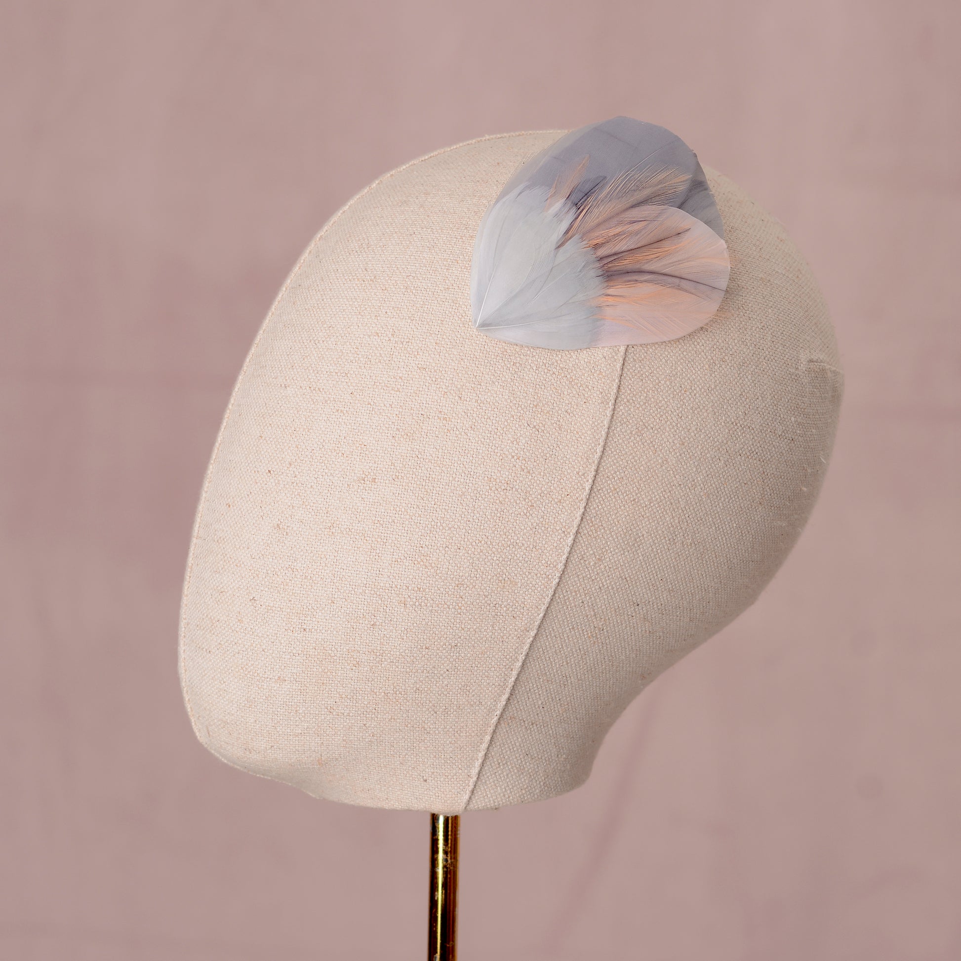 Mannequin head with a decorative feather hair clip in grey and blush pink