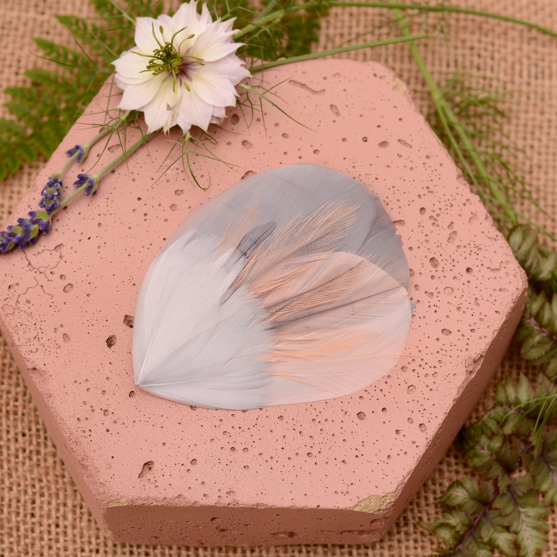 Hexagonal pink stone wih  a feather hair clip in grey and blush pink with flowers and leaves.