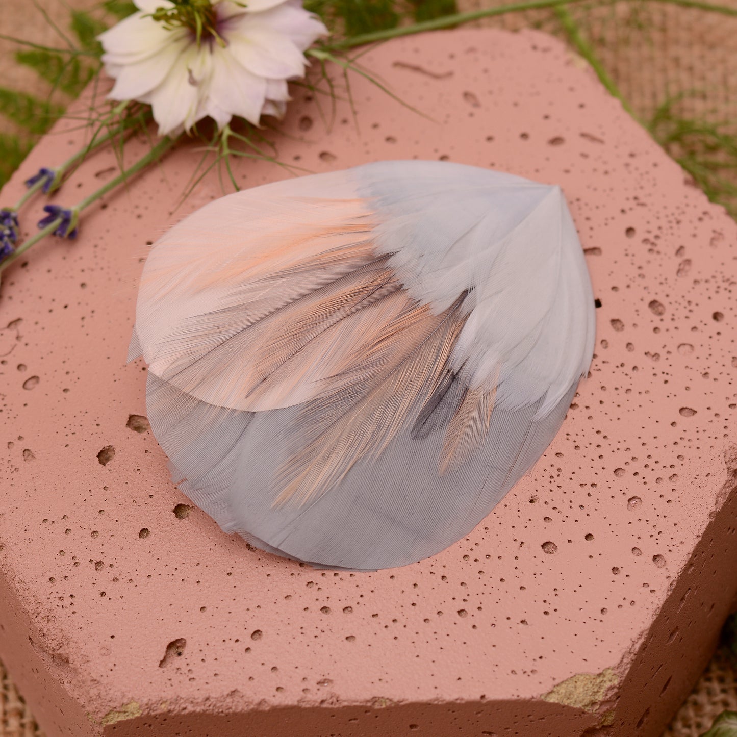 Hexagonal pink stone wih  a feather hair clip in grey and blush pink with flowers and leaves.