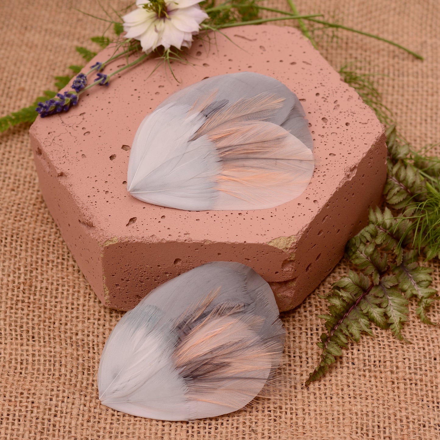 Hexagonal pink stone wih  a pair of feather hair clip in grey and blush pink with flowers and leaves.