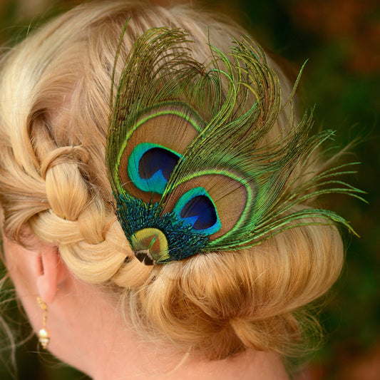 Woman with braided hair adorned with a peacock feather clip against a blurred natural background