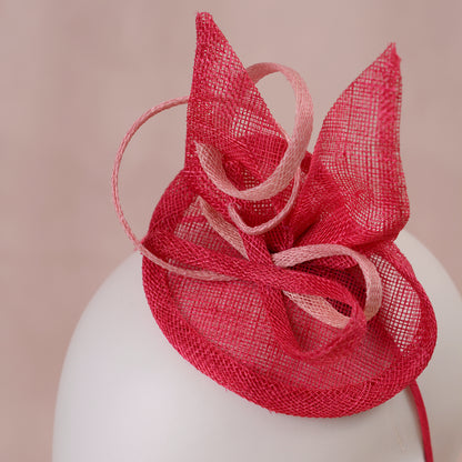 Close up of a pink sinamay side perching fascinator in two shades of tonal pink displayed on a white mannequin head against a soft pink background.
