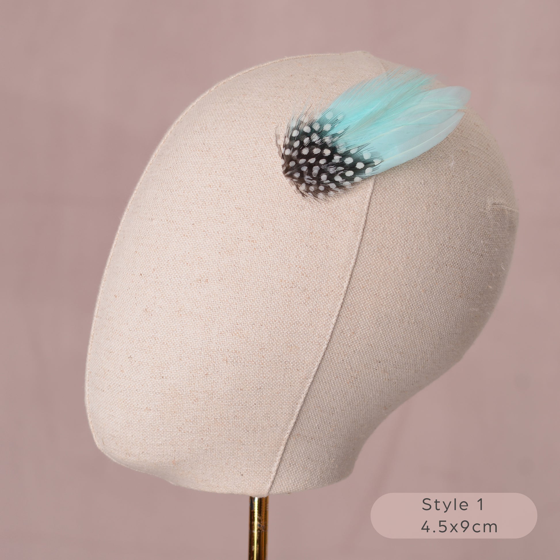Mint green and polka dot Feather hair accessory on a mannequin head with a pink background