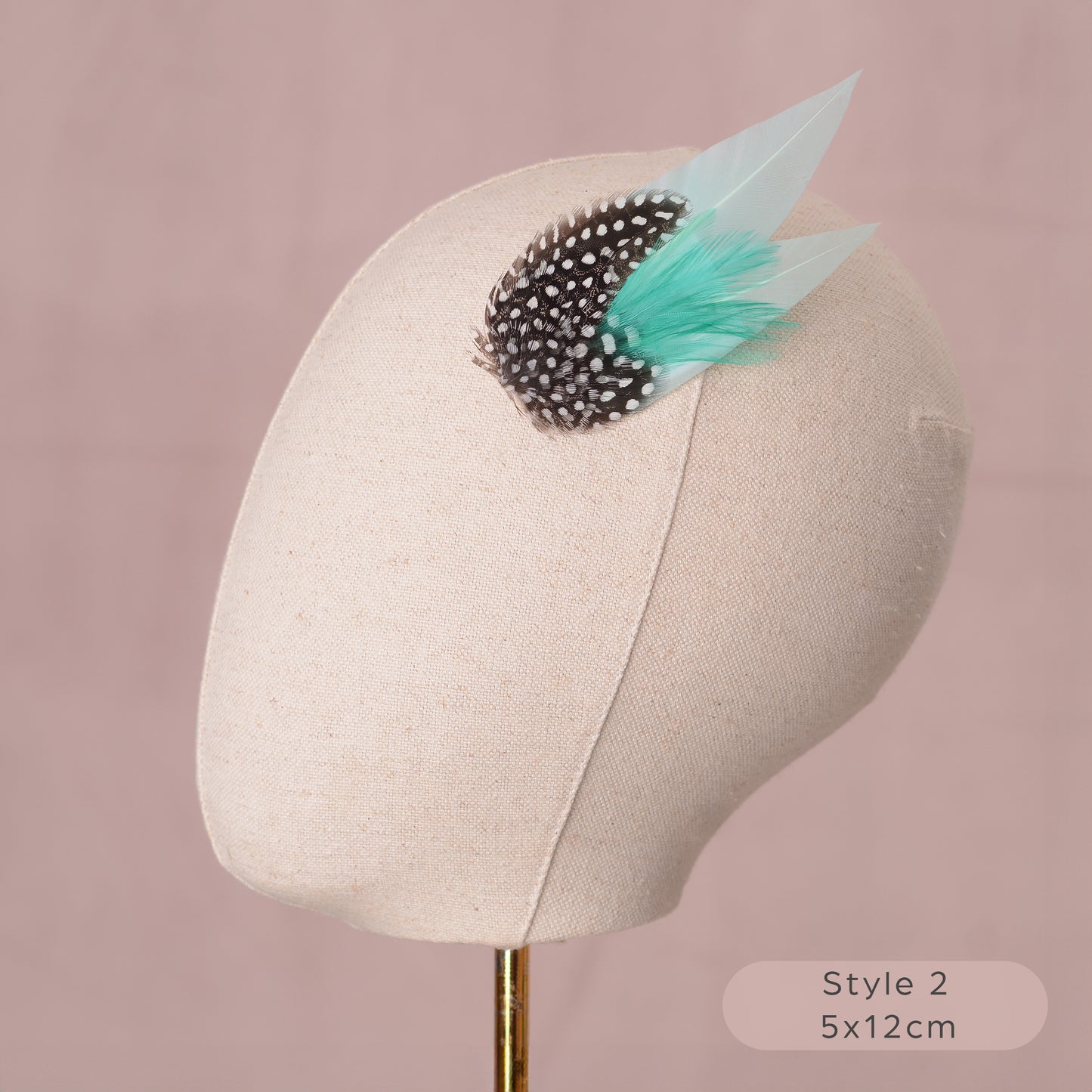 Mint green and polka dot Feather hair accessory on a mannequin head with a pink background