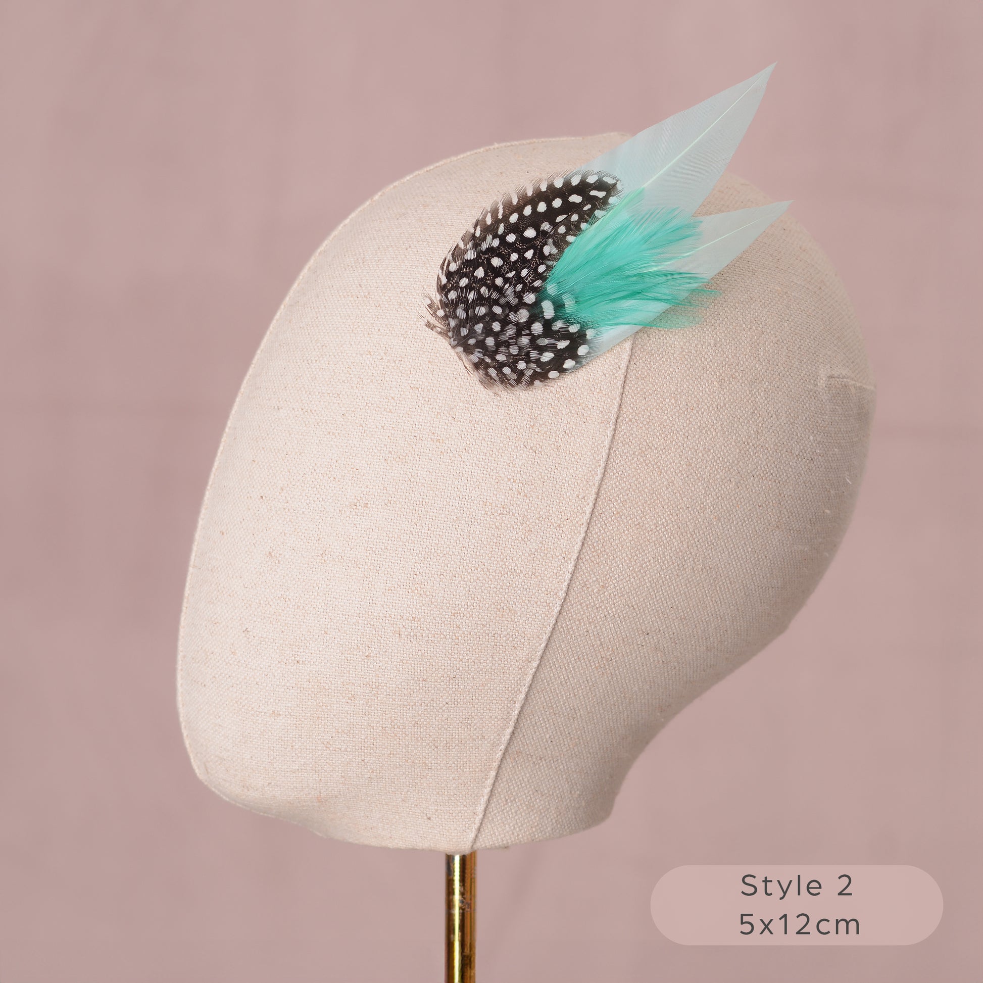 Mint green and polka dot Feather hair accessory on a mannequin head with a pink background