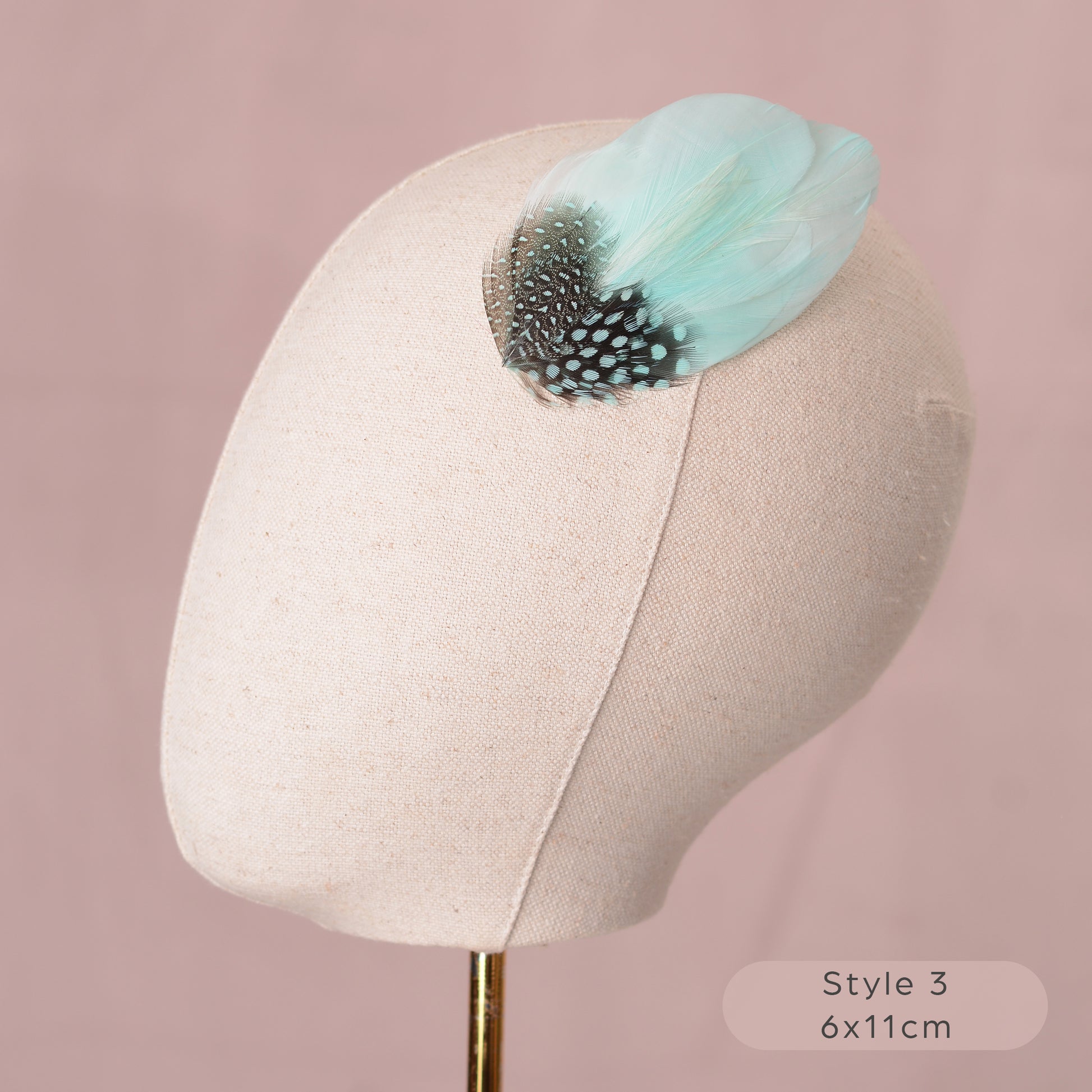 Mint green and polka dot Feather hair accessory on a mannequin head with a pink background