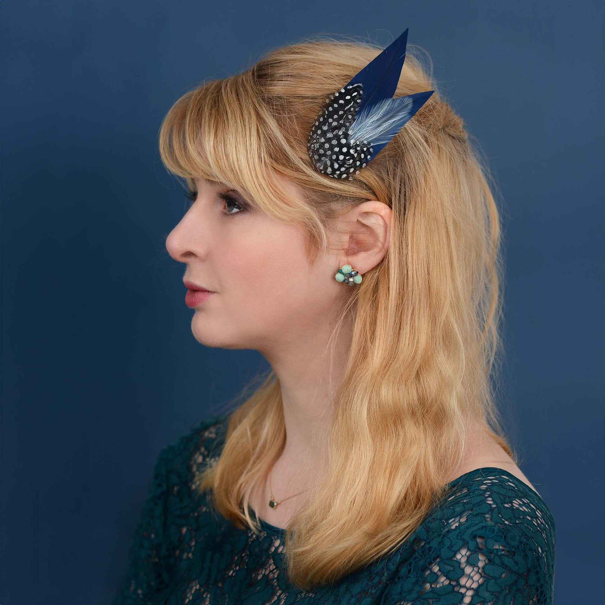 Woman with blonde hair and decorative navy blue feather hair clip fascinator 