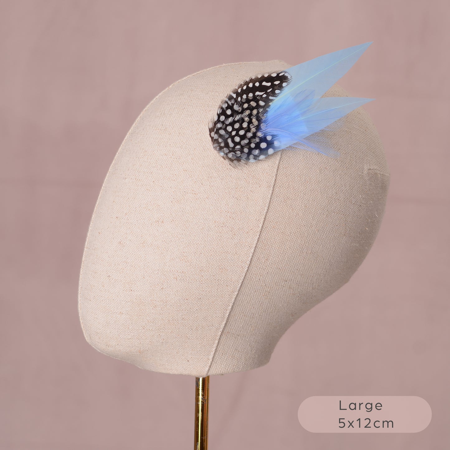 Mannequin head with a decorative blue feather hair clip on a pink background