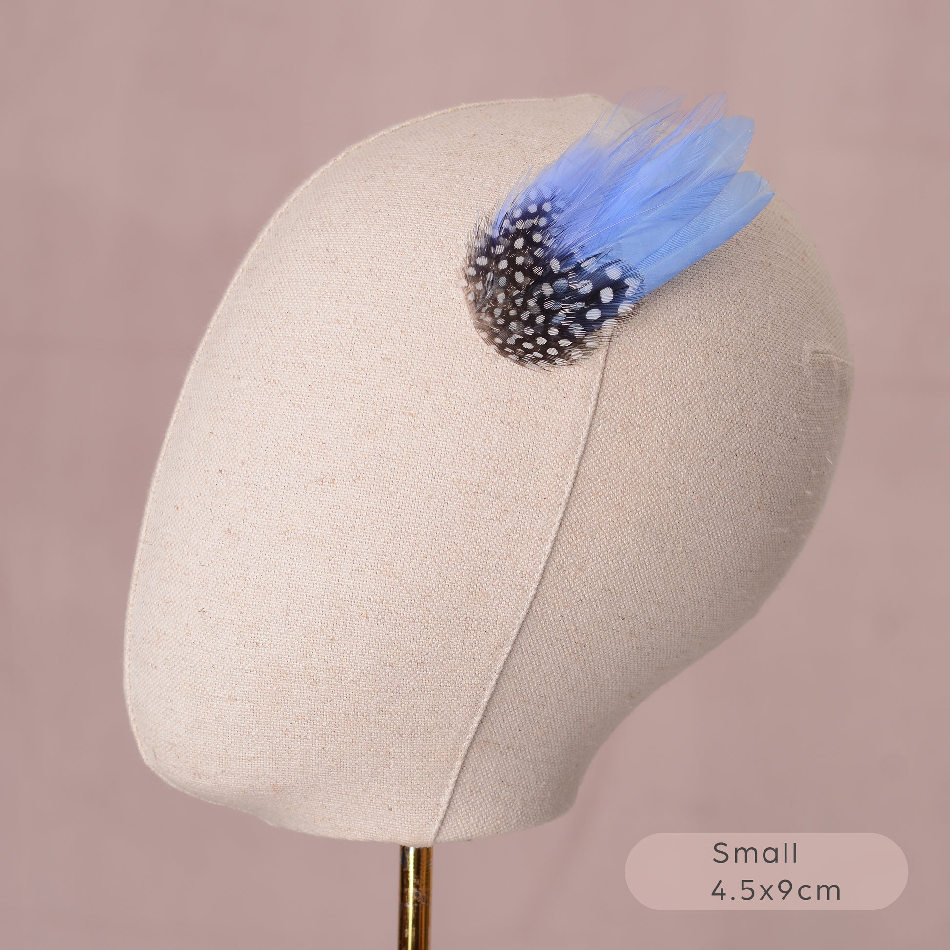 Mannequin head with a decorative blue feather hair clip on a pink background
