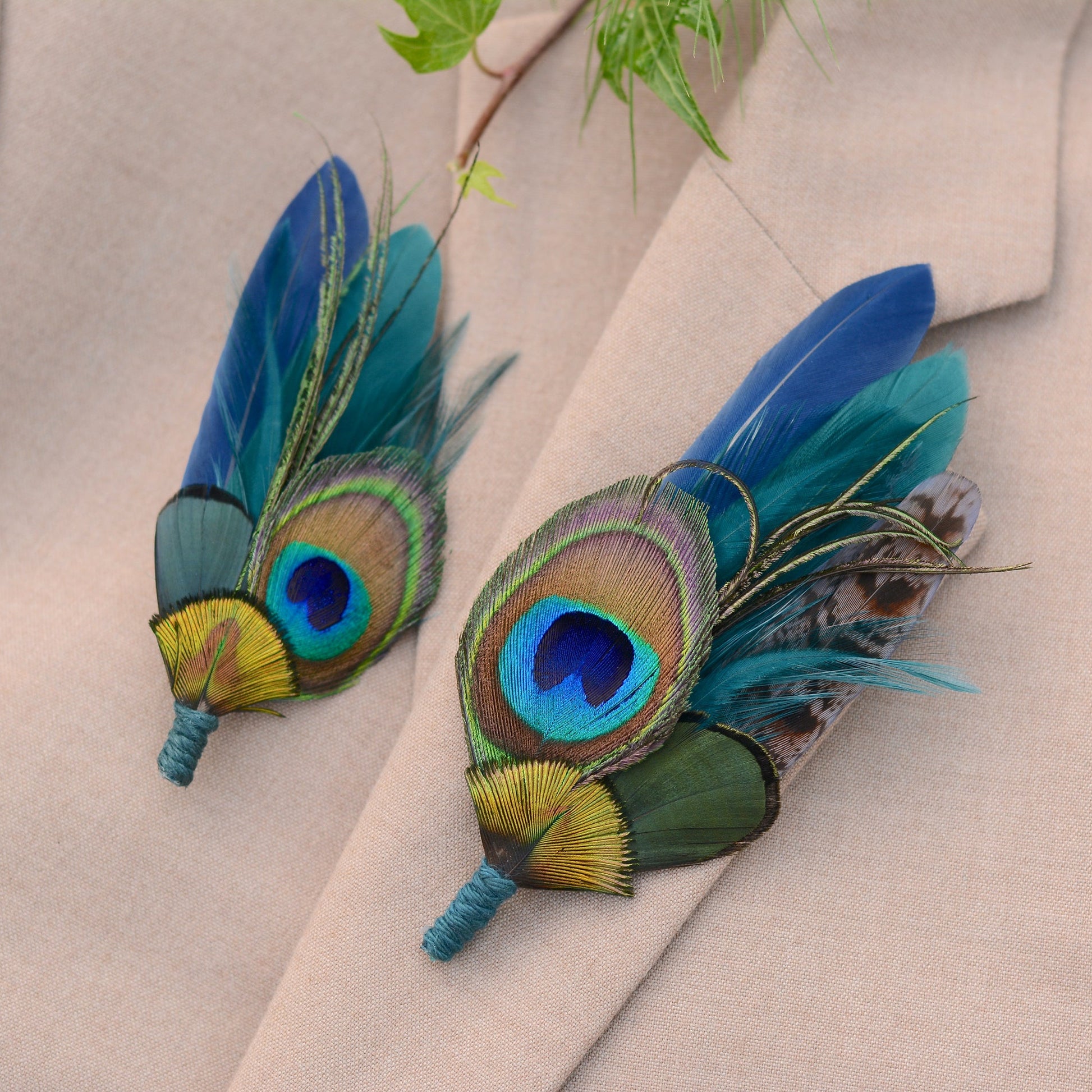 Two peacock feather boutonnieres on a beige suit jacket.