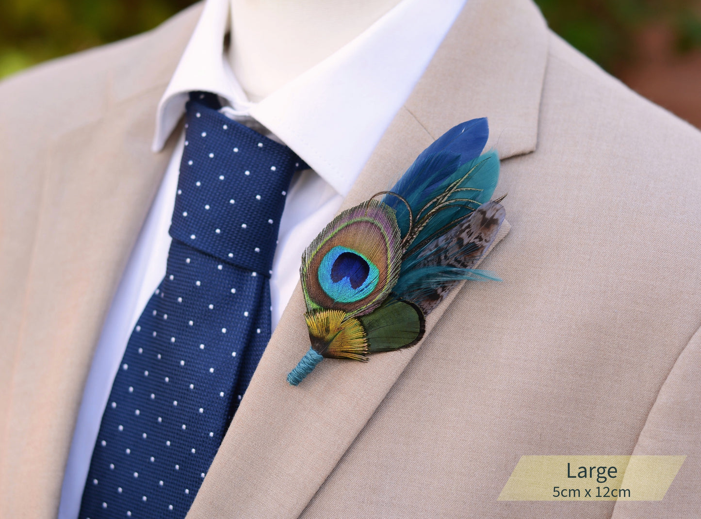 Beige suit jacket with a blue polka dot tie and peacock feather boutonniere.