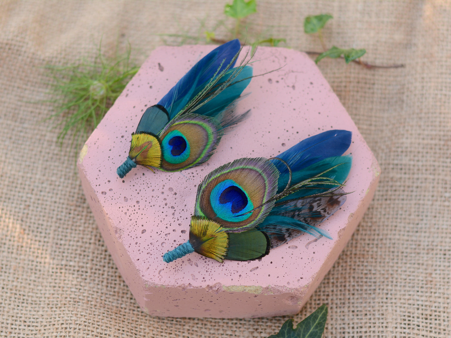 Hexagonal pink stone with matching peacock feather buttonholes on a textured beige background