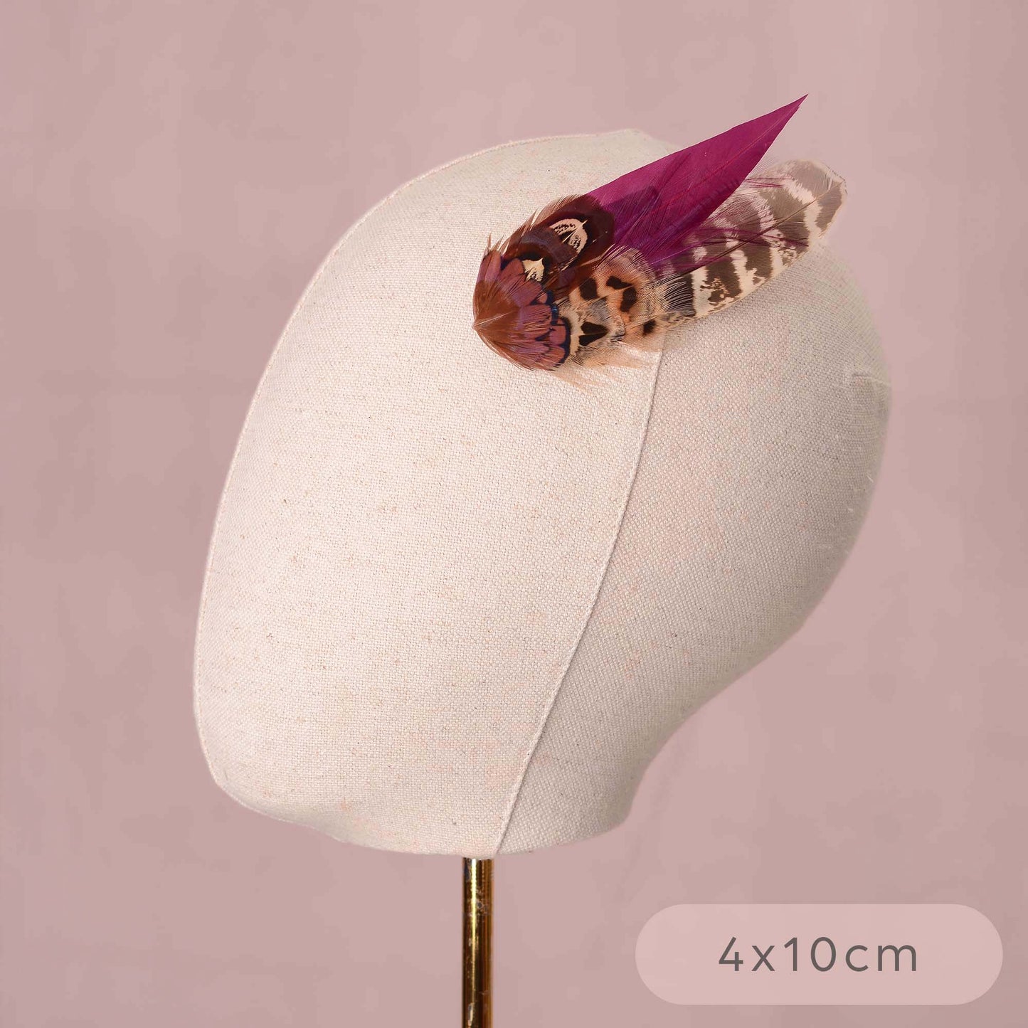 A pheasant feather hair clip fascinators with vibrant purple and brown patterns on a canvas mannequin head