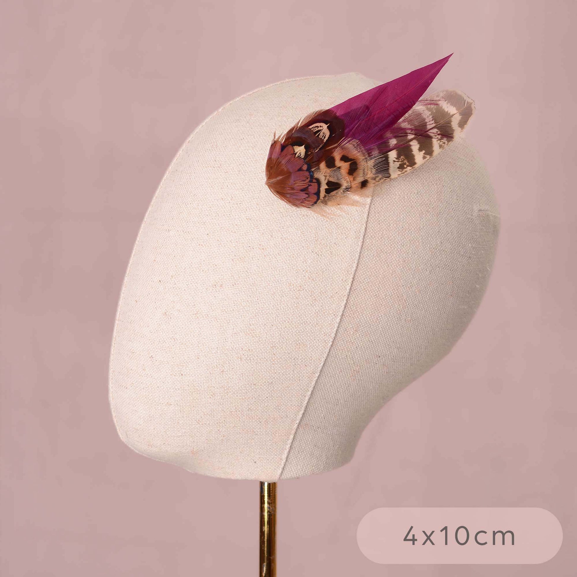 A pheasant feather hair clip fascinators with vibrant purple and brown patterns on a canvas mannequin head